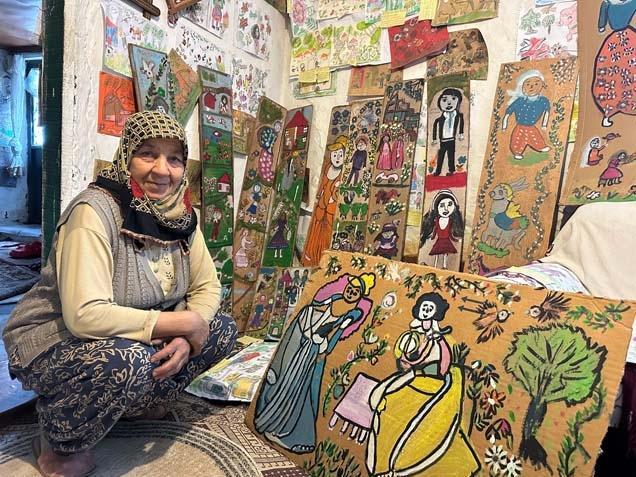 KARTONLARA, AĞAÇ İLE TAŞ PARÇALARINA VE KAĞITLARA RESİM ÇİZİYOR